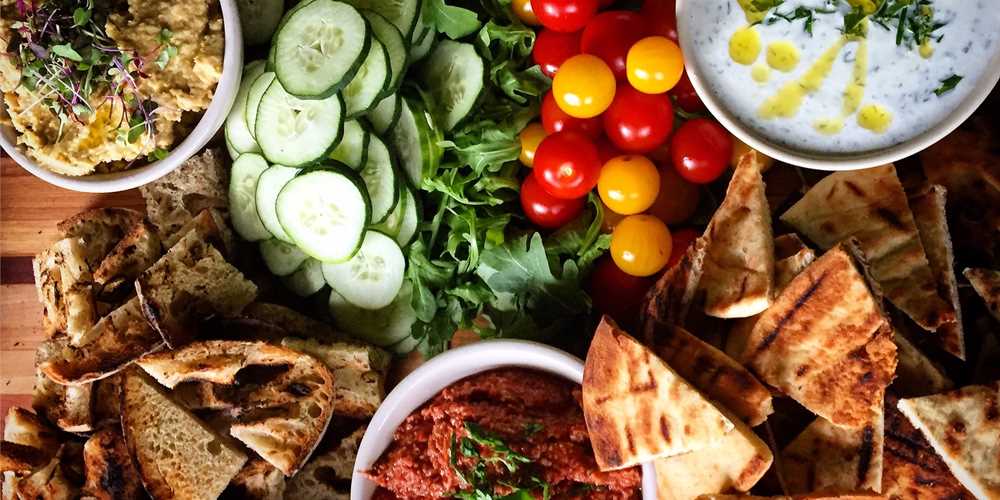 Meze platter with hummus, walnut salsa, tzatziki, cucumber, olives, cherry tomato, & pita chips